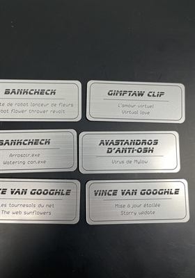 Série de plaquettes nominatives bilingues gravées pour l’identification d’œuvres exposées
