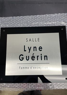 Plaque de porte en aluminium brossé montée sur acrylique noir, nommant une salle